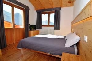 a bedroom with a bed and two windows at Adda Vegia in Buglio in Monte