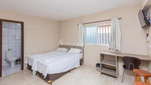1 dormitorio con cama, aseo y ventana en Estúdios confortáveis com preços acessíveis totalmente mobiliados, en Curitiba