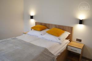Un dormitorio con una cama con dos almohadas amarillas. en MoKa Apartamenty Sianożęty, en Sianożęty 45 fotos más