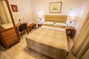 a room with two beds and a table and a desk at Pousada Bahia Pelô in Salvador