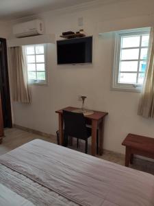 a bedroom with a desk and a television on the wall at Pousada Bahia Pelô in Salvador