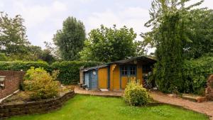 une petite maison jaune et bleue dans une cour dans l'établissement Sfeervol 't Rustpunt, à Bierum