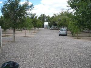 un coche aparcado en un aparcamiento de grava con árboles en Guardalaola en Las Grutas