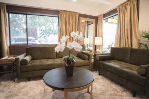 a living room with two couches and a table with flowers at Robin Hood Inn and Suites in Victoria