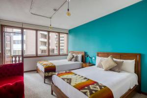 1 dormitorio con 2 camas y sofá rojo en Selina Quito en Quito