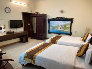 a hotel room with two beds and a flat screen tv at Thang Long Hotel in Hanoi