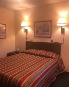 Habitación de hotel con 1 cama y 2 luces en la pared en Luxury Inn, en Cheyenne
