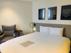 a bedroom with a bed and a chair and pictures on the wall at GLAD Gangnam COEX Center in Seoul
