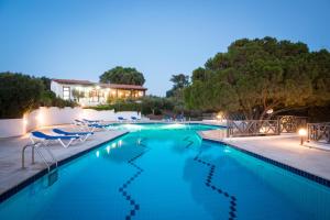 une piscine avec des chaises et un bâtiment en arrière-plan dans l'établissement Ambelos, à Agia Pelagia
