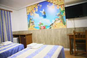 Habitación con 2 camas y TV en la pared. en Hotel plaza en Riaza