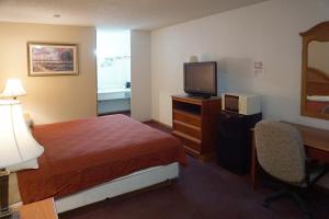a hotel room with a bed and a desk and a television at OYO Hotel Altus N Main St in Altus