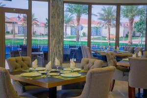a dining room with tables and chairs and a pool at Swiss Luxury Villas in Unayzah