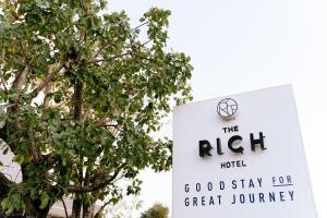 una señal para el motel correcto junto a un árbol en The Rich Hotel, en Nakhon Ratchasima