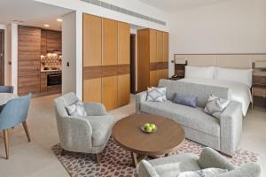 a living room with a bed and a couch and chairs at Staybridge Suites Dubai Al-Maktoum Airport by IHG in Dubai