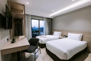a hotel room with two beds and a desk at The Rich Hotel in Nakhon Ratchasima