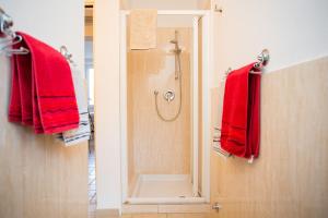 bagno con doccia e asciugamani rossi di La Casa della Tilde a Bocca di Magra