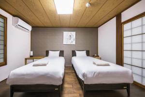 2 camas en una habitación con 2 ventanas en Shiki Homes NENE en Kyoto