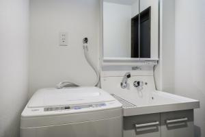 Baño blanco con lavabo y espejo en Shiki Homes NENE en Kyoto