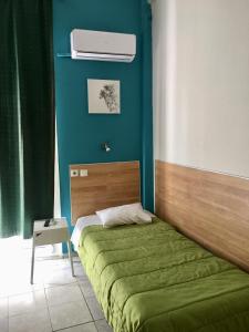 a bedroom with a bed with a green bedspread at Hotel Kastoria in Thessaloniki