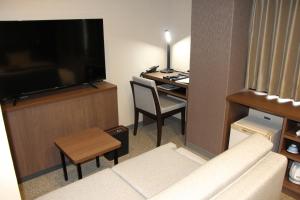 a living room with a couch and a television and a desk at Matsue Urban Hotel in Matsue