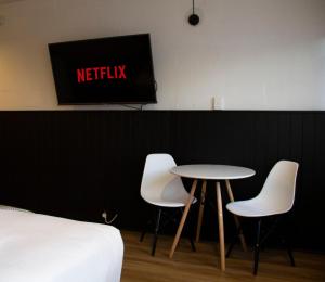 a table and two chairs and a tv on a wall at SoYa on Davis Apartment Hotel in Melbourne