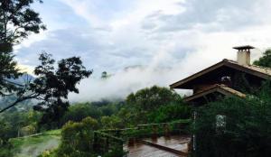 a house with a view of a mountain with clouds at Pousada Villa Catarina in Gonçalves