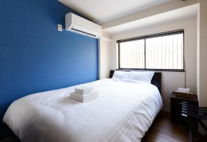 a bedroom with a white bed with a blue wall at Shiki Homes KURUMI in Osaka