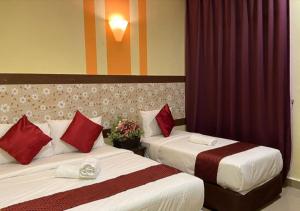 two beds in a hotel room with red pillows at SUN INNS PERMAS JAYA in Johor Bahru