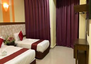 a hotel room with two beds and purple curtains at SUN INNS PERMAS JAYA in Johor Bahru