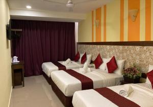 a hotel room with three beds with red pillows at SUN INNS PERMAS JAYA in Johor Bahru