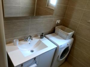 a bathroom with a sink and a washing machine at Korkyra Melaina in Korčula