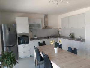 a white kitchen with a wooden table and chairs at Korkyra Melaina in Korčula
