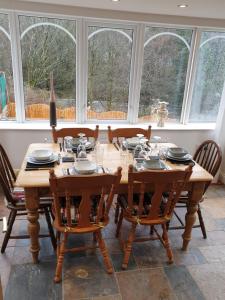 een eetkamer met een tafel, stoelen en ramen bij Riverside cottage in Treherbert