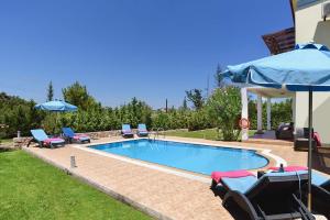 a pool with chairs and umbrellas next to a house at Seven Springs Villas in Kolymbia