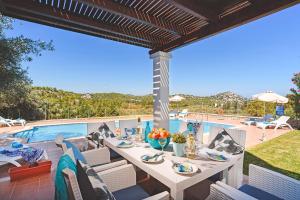 een patio met een tafel en stoelen naast een zwembad bij Seven Springs Villas in Kolimbia