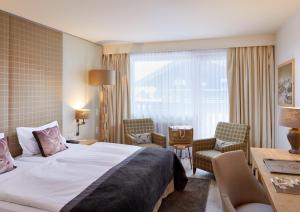 a hotel room with a bed and chairs and a desk at Das Alpenhaus Kaprun inkl Zell am See-Kaprun Sommerkarte in Kaprun