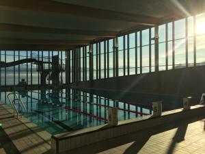 a swimming pool in a building with the sun shining through the windows at Hardangerfjord Hotel in Øystese