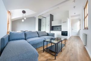 a living room with a blue couch and a glass table at Apartamenty Sun & Snow Międzyzdroje Promenada in Międzyzdroje