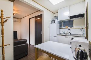 Una cocina con un refrigerador blanco y una mesa. en Shiki Homes KURIKO, en Osaka