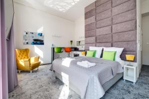 SAVOY Mariacka Apartments في كاتوفيسي: غرفة نوم بسرير كبير وكرسي اصفر