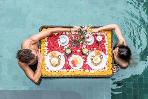 two people in a pool with a cake in the water at Villa DeDayuh Seminyak in Seminyak