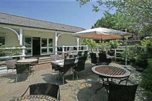 a patio with tables and chairs and an umbrella at Wingrove House in Alfriston