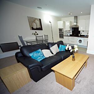 a living room with a black leather couch and a table at Premier Apartments in Bradford