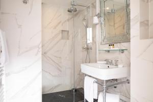 a white bathroom with a sink and a shower at Odeon Hotel by Malone in Paris