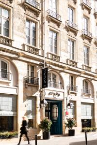 une personne qui passe devant un bâtiment avec une porte verte dans l'établissement Odeon Hotel by Malone, à Paris