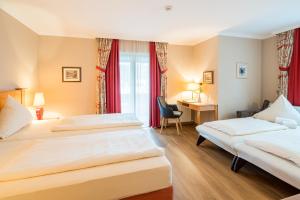 a hotel room with two beds and a desk at Hotel-Gasthof Huber in Ebersberg