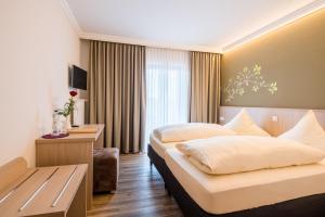 a hotel room with two beds and a desk at Hotel-Gasthof Huber in Ebersberg