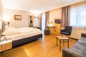 ein Hotelzimmer mit einem Bett und einem Sofa in der Unterkunft Hotel-Gasthof Huber in Ebersberg