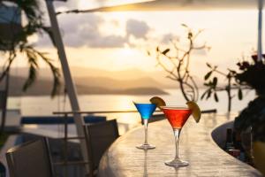 three cocktails on a table with a view of the ocean at UniQue BoutiQue Resort in Bang Rak Beach