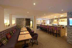 um restaurante com mesas e cadeiras de madeira e um bar em Alpenhotel Fleurs de Zermatt em Zermatt